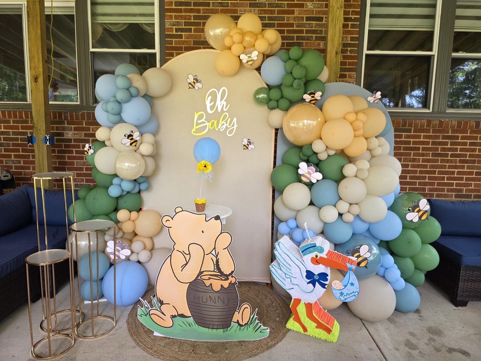 Winnie the Pooh baby shower backdrop with bees, soft balloons, and themed props