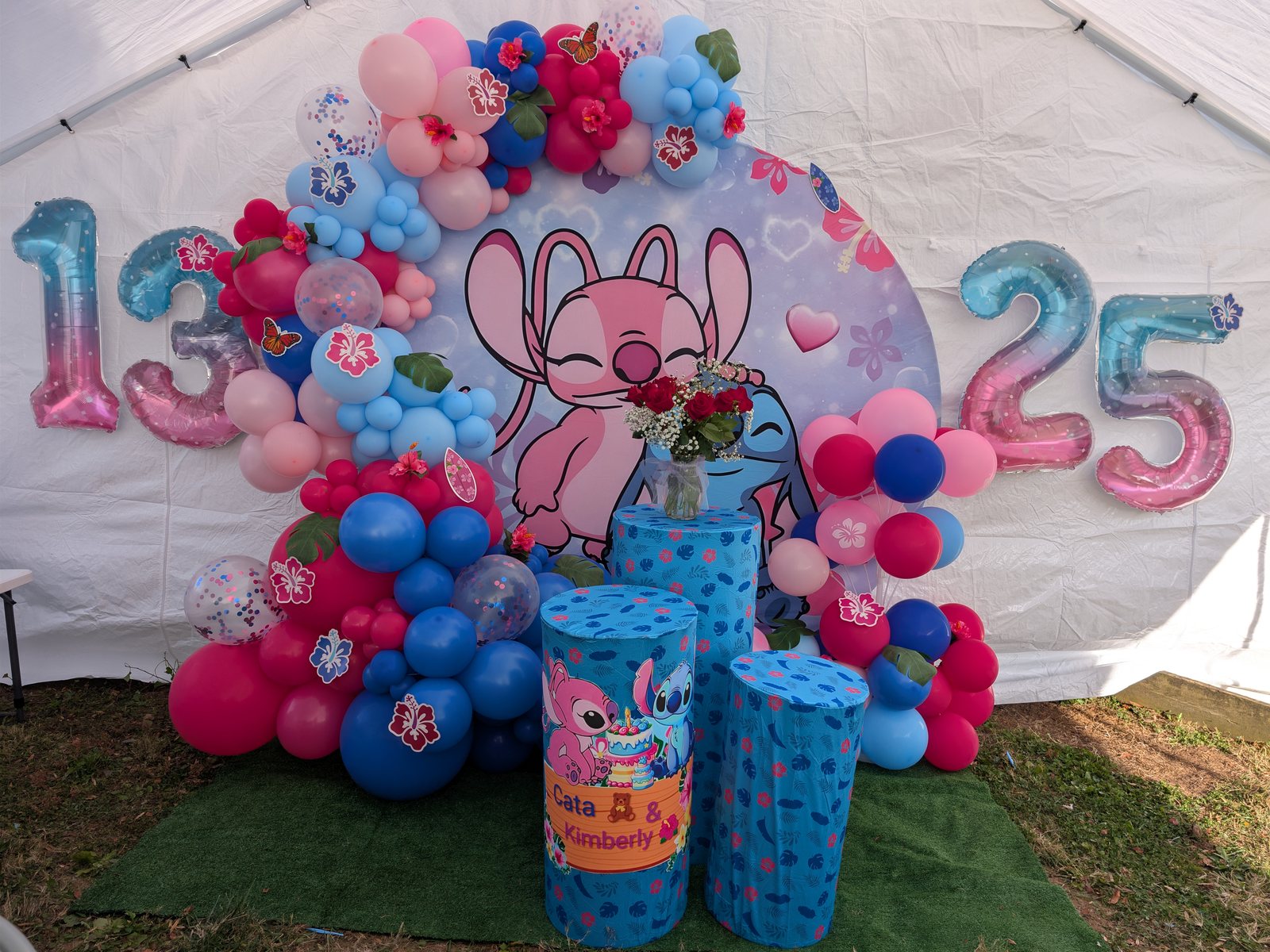 Stitch themed birthday backdrop with bright pink and blue balloons, custom cylinders, and number balloons
