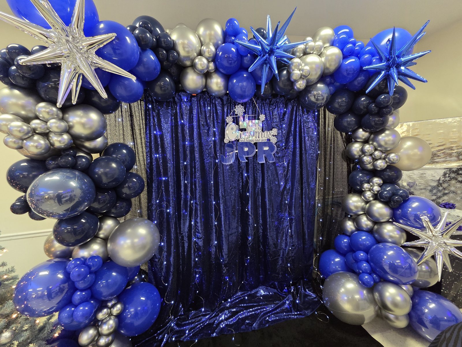 Blue and silver winter event backdrop with metallic balloon stars and string lights