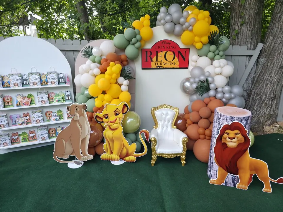 Lion King first birthday balloon backdrop with character props and gold chair