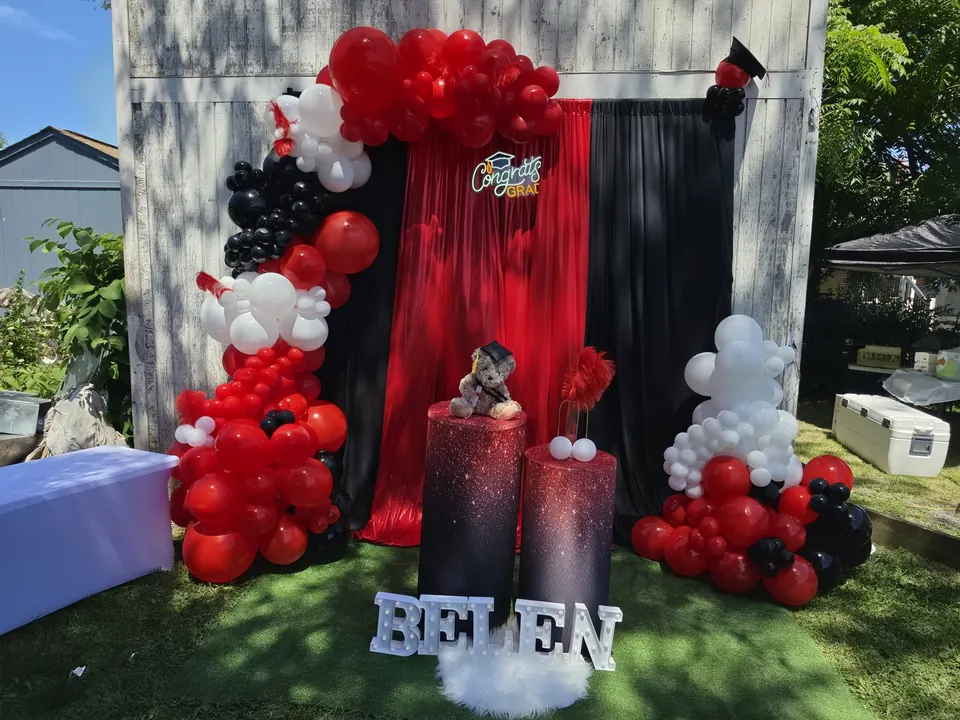 Red, black, and white graduation decor with draping, balloons, and marquee name letters