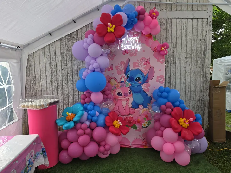 Floral Stitch themed birthday decor with pink and blue balloons, tropical flowers, and custom backdrop