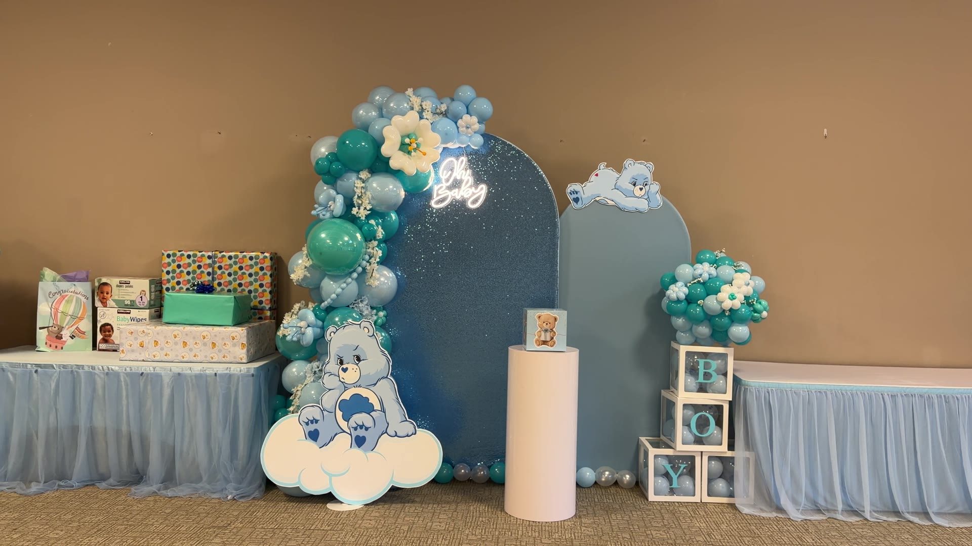 Baby shower film still with blue shimmer backdrop, balloons, florals, and themed props